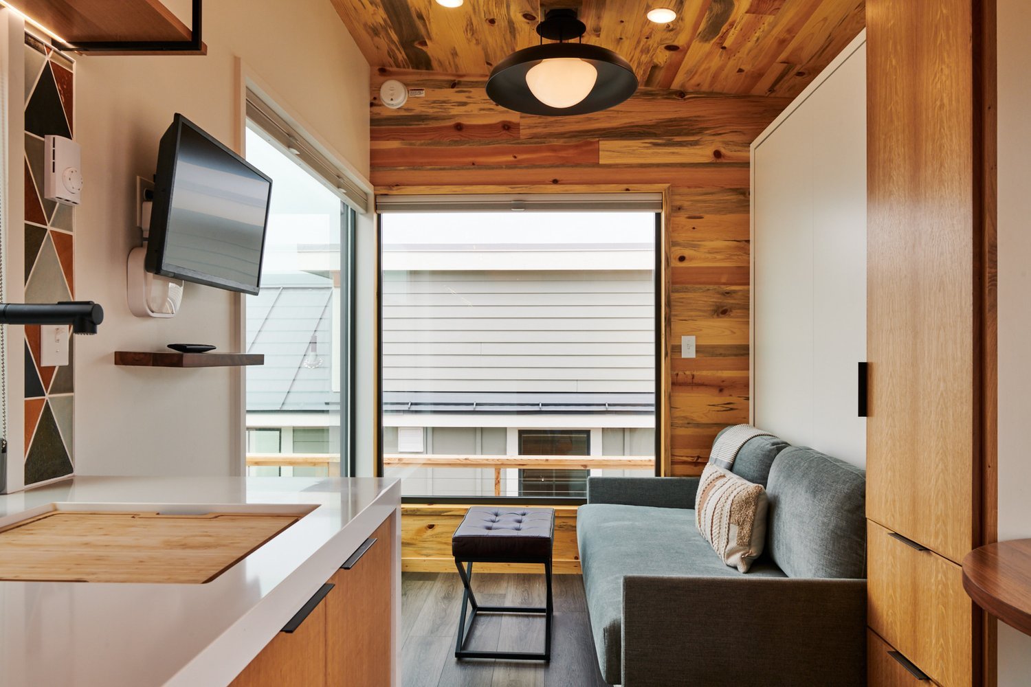 A living room in an Osprey cabin featuring light wood bunk beds with coastal-themed bedding and white wood-paneled walls.