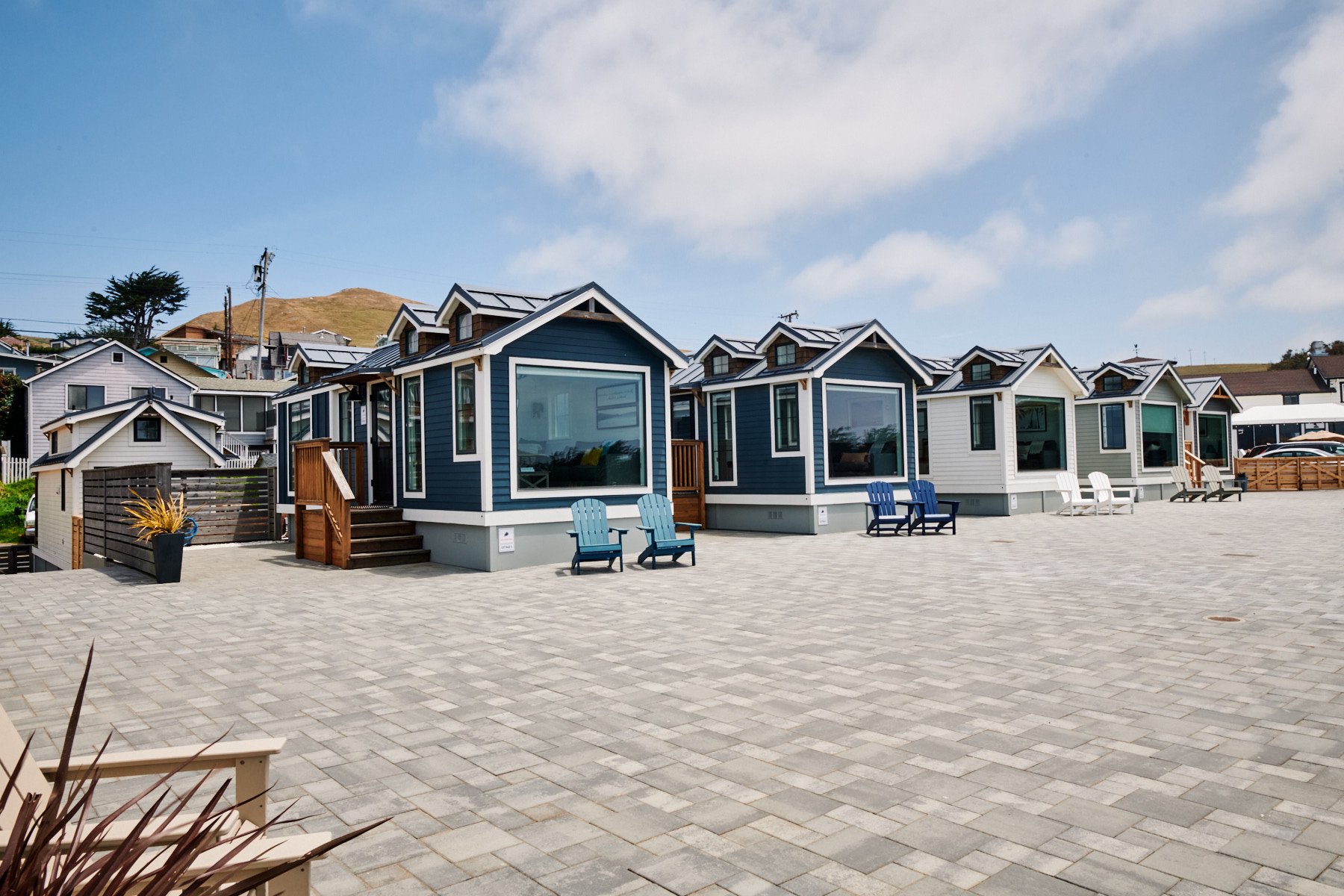 Private stone-paved deck of a Sweetwater cabin at ブライトリビエラ, showing a wooden picnic table and Adirondack chairs overlooking the beach.
