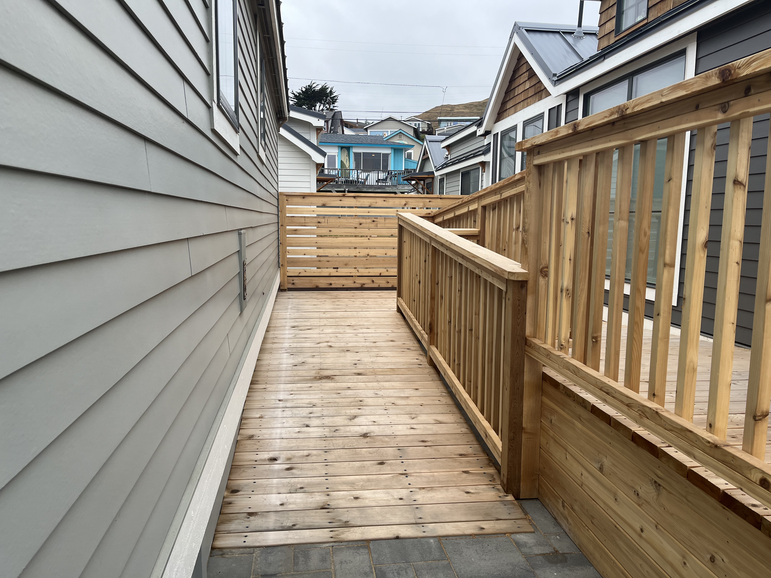 A wide, gently sloped wooden accessibility ramp with sturdy handrails leading to the cottage entrance.