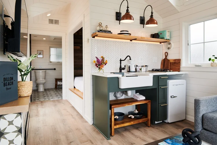 Modern tiny house at ブライトリビエラ with forest green cabinets, farmhouse sink, and views of the bedroom and bath.